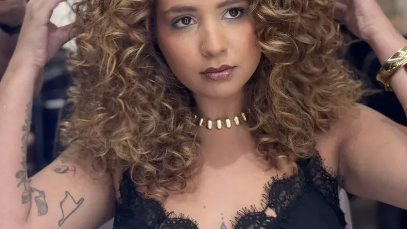 Morena iluminada con reflejos cálidos y rizos definidos